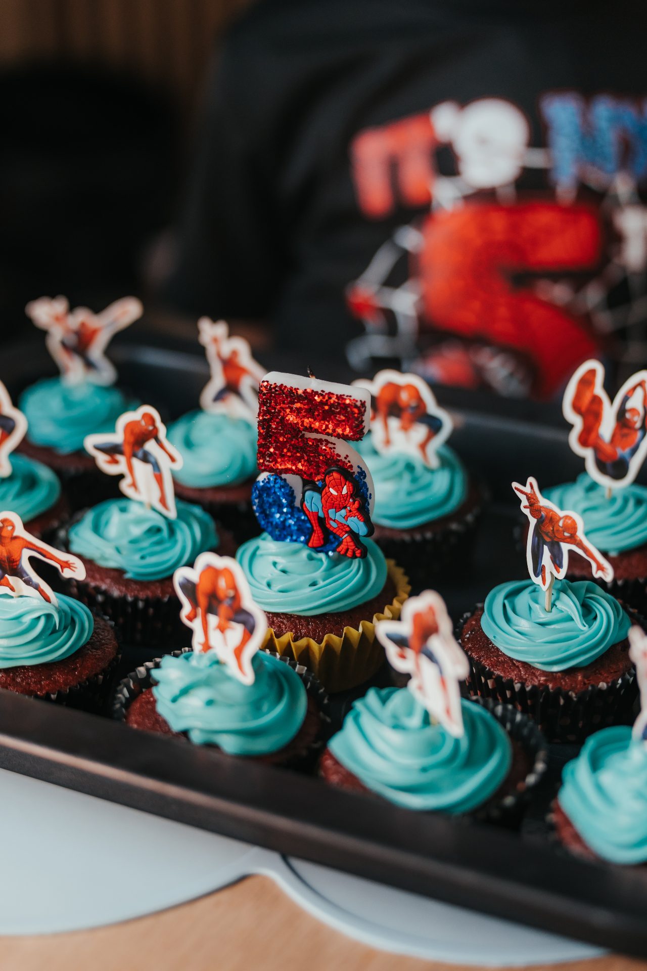 Anniversaire thème Spider-Man chez Slime Art Studio — cupcakes au glaçage bleu turquoise avec figurines Spider-Man et bougie pailletée numéro 5