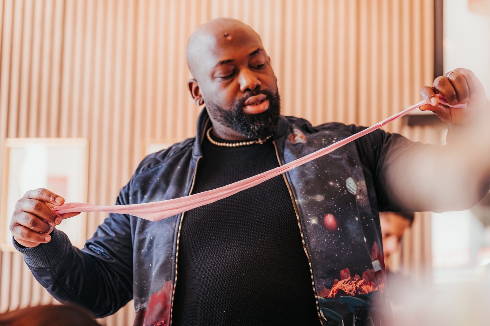 Atelier Slime Art Studio — animateur étirant une slime rose devant les participants dans une salle lumineuse aux murs en tasseaux de bois