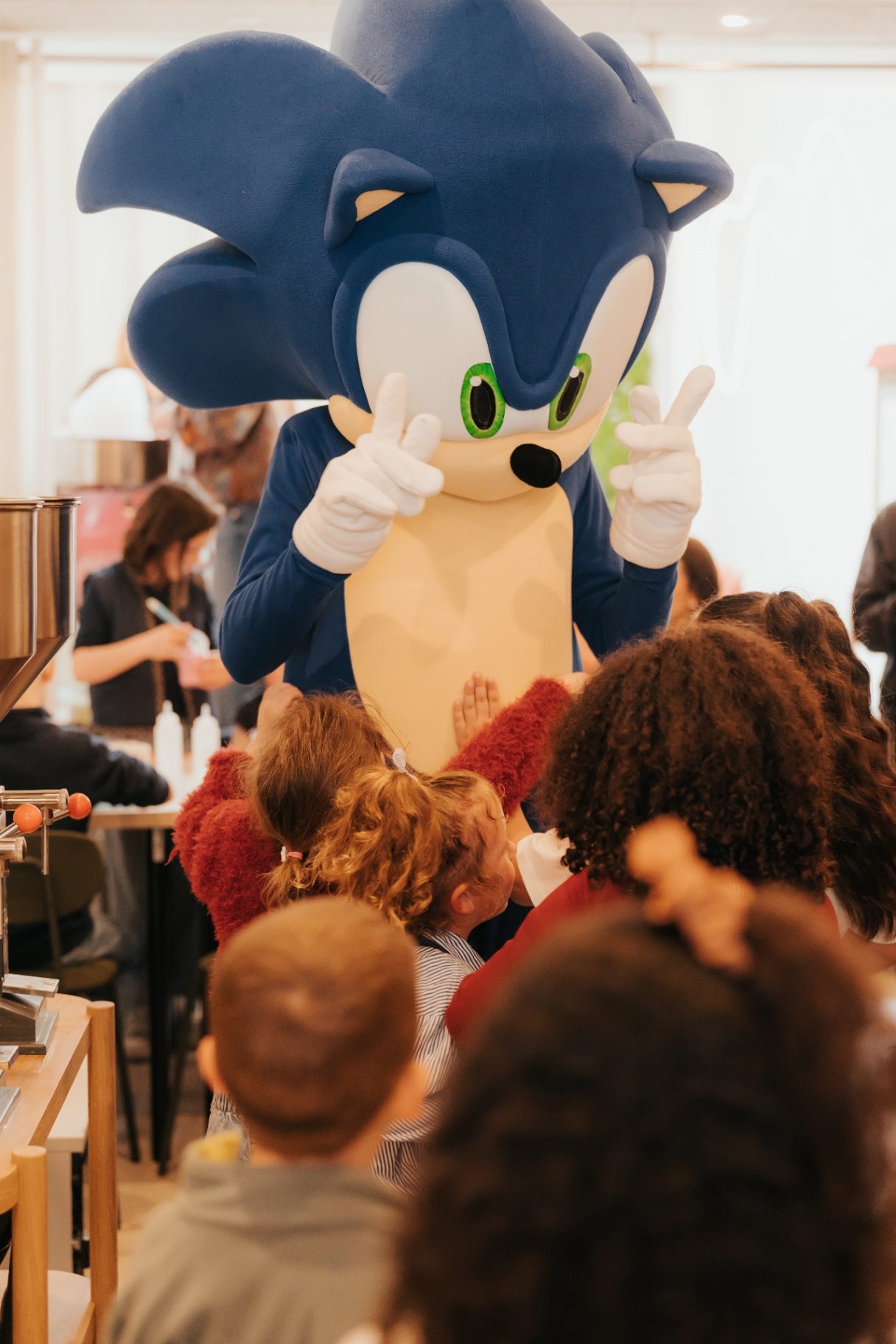 Slime Art Studio — mascotte Sonic géante faisant le signe de la victoire au milieu d'un groupe d'enfants émerveillés dans le studio